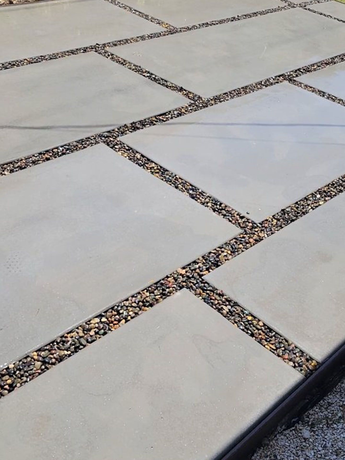 A concrete driveway with a pattern of squares and gravel