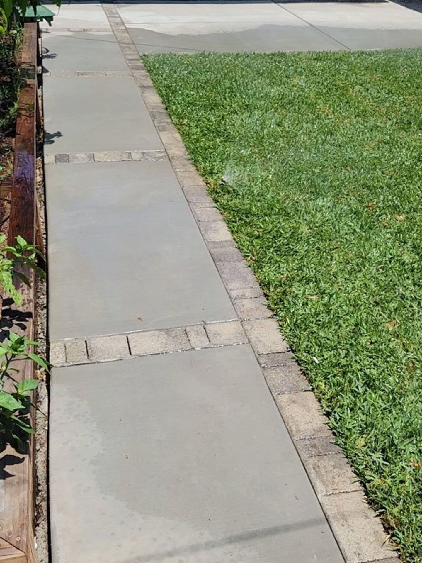 A concrete walkway leading to a lush green lawn.