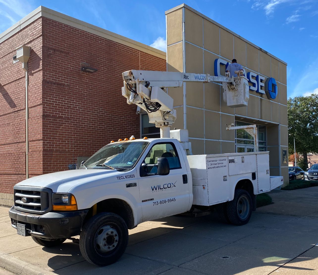 Man being lifted by a bucket truck while fixing a sign