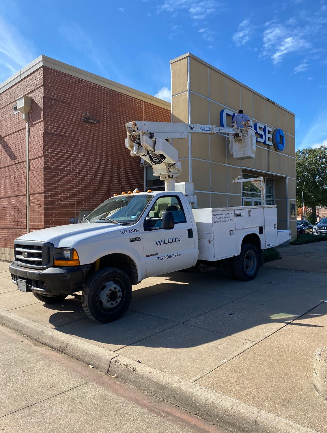 Man being lifted by a bucket truck while fixing a sign