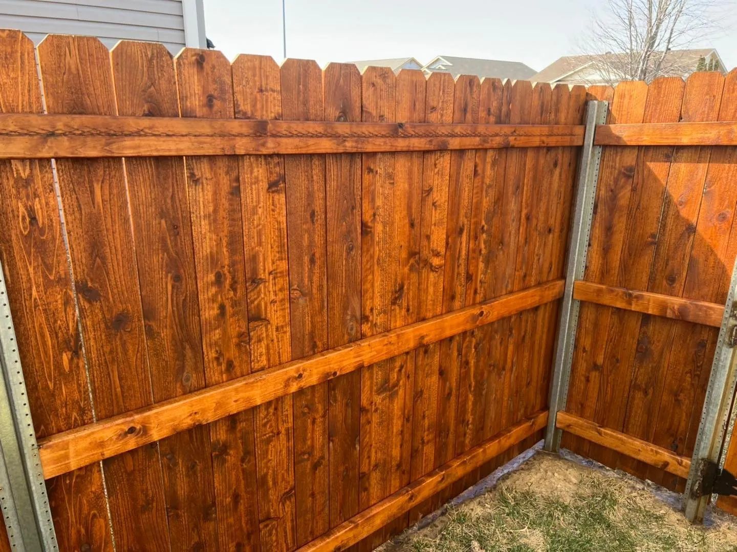 A wooden fence is sitting next to a sidewalk in front of a building.
