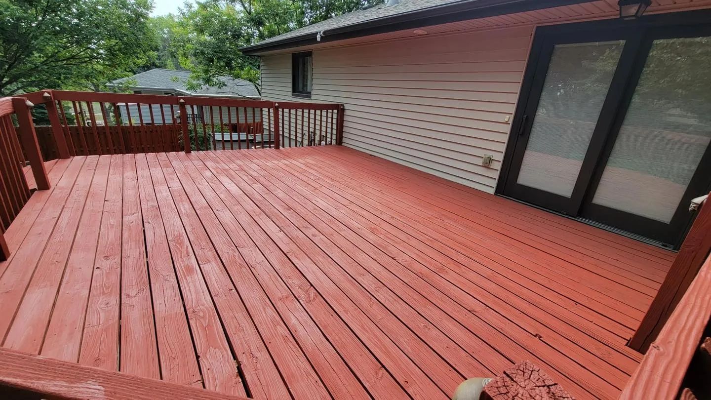 A wooden deck is sitting in front of a gray house.