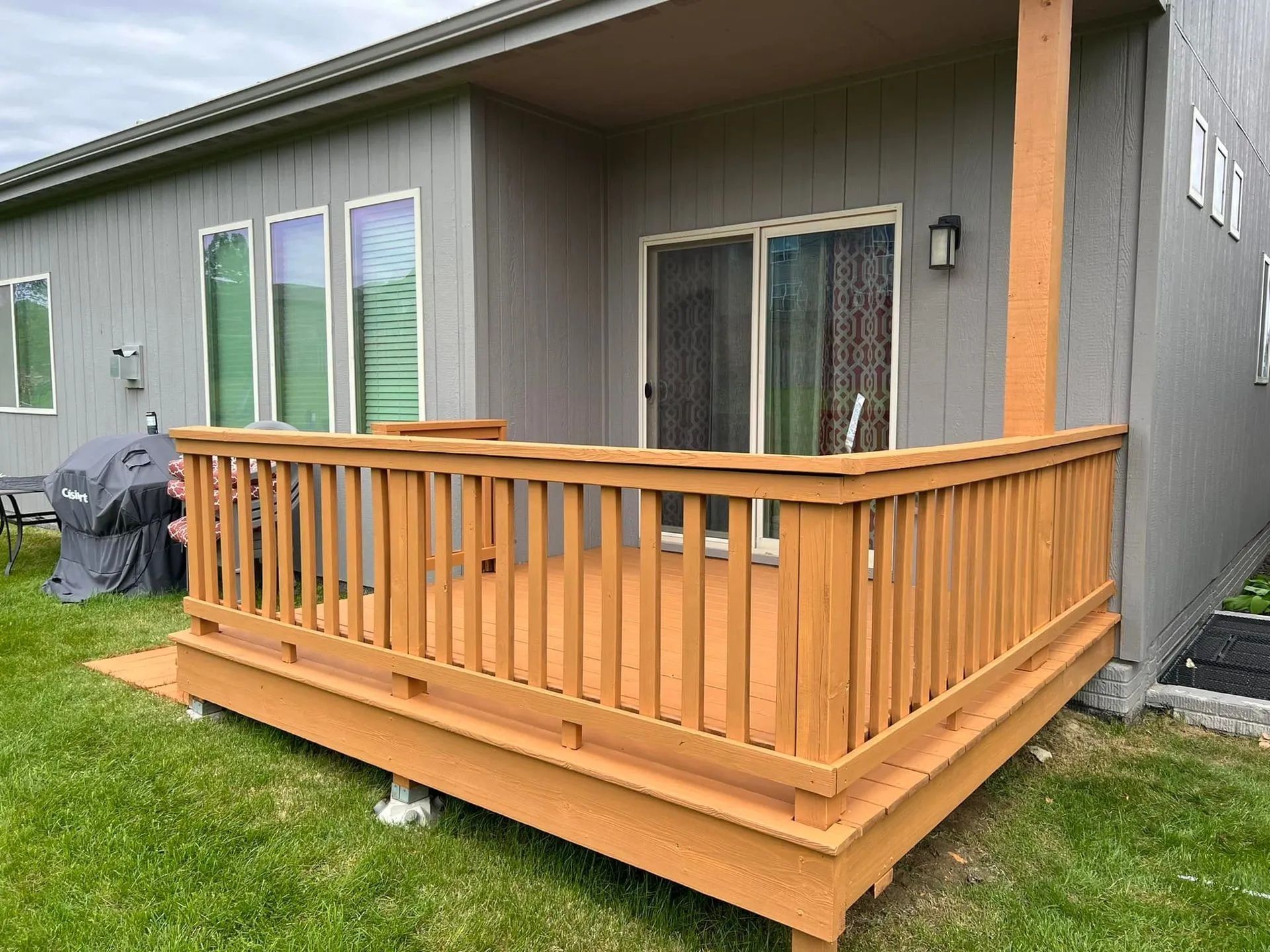 A red wooden deck with a white house in the background.