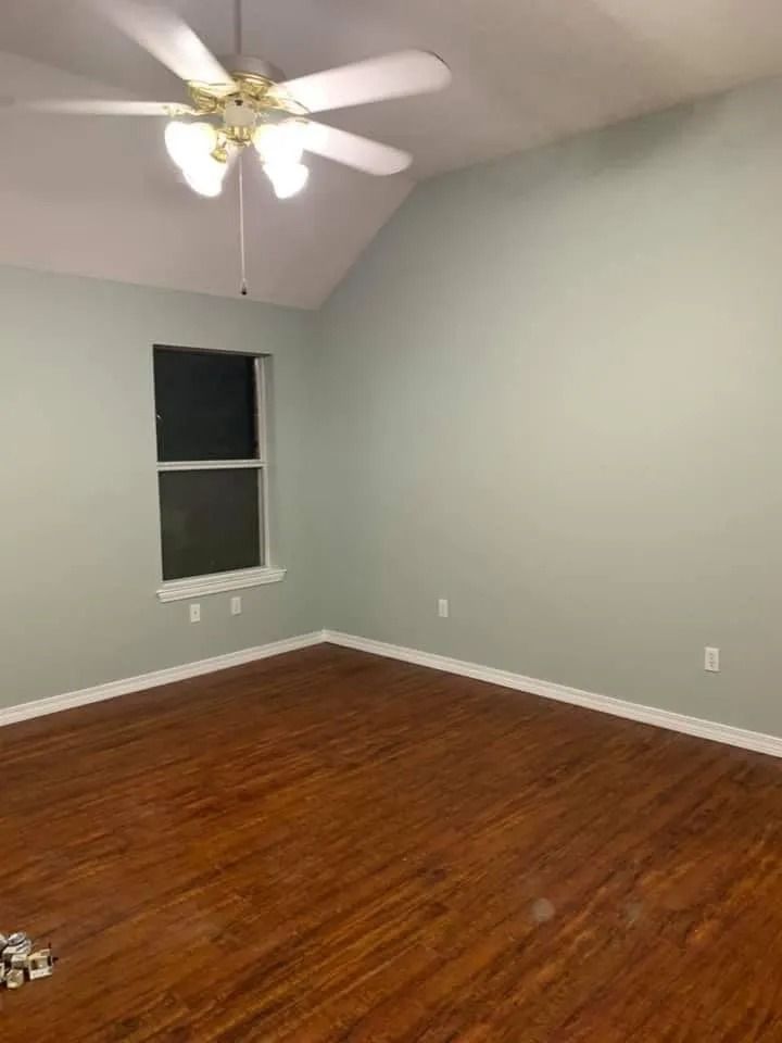 An empty bedroom with hardwood floors and a ceiling fan.
