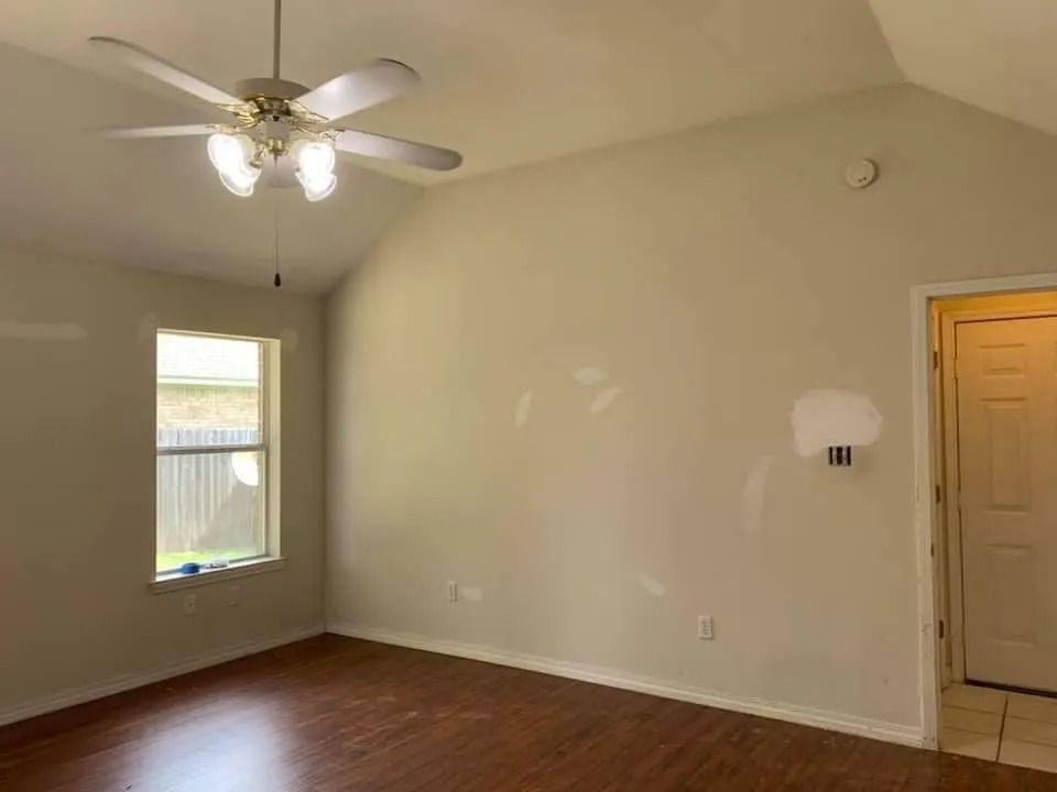 An empty room with a ceiling fan and a window.