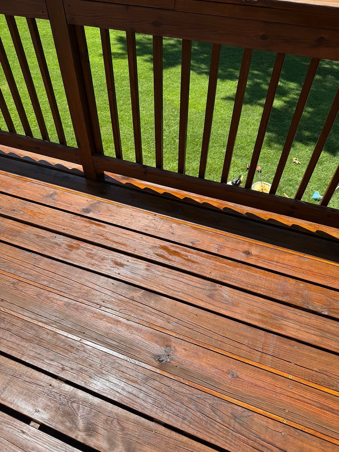 A wooden deck with stairs leading up to it is in front of a house.