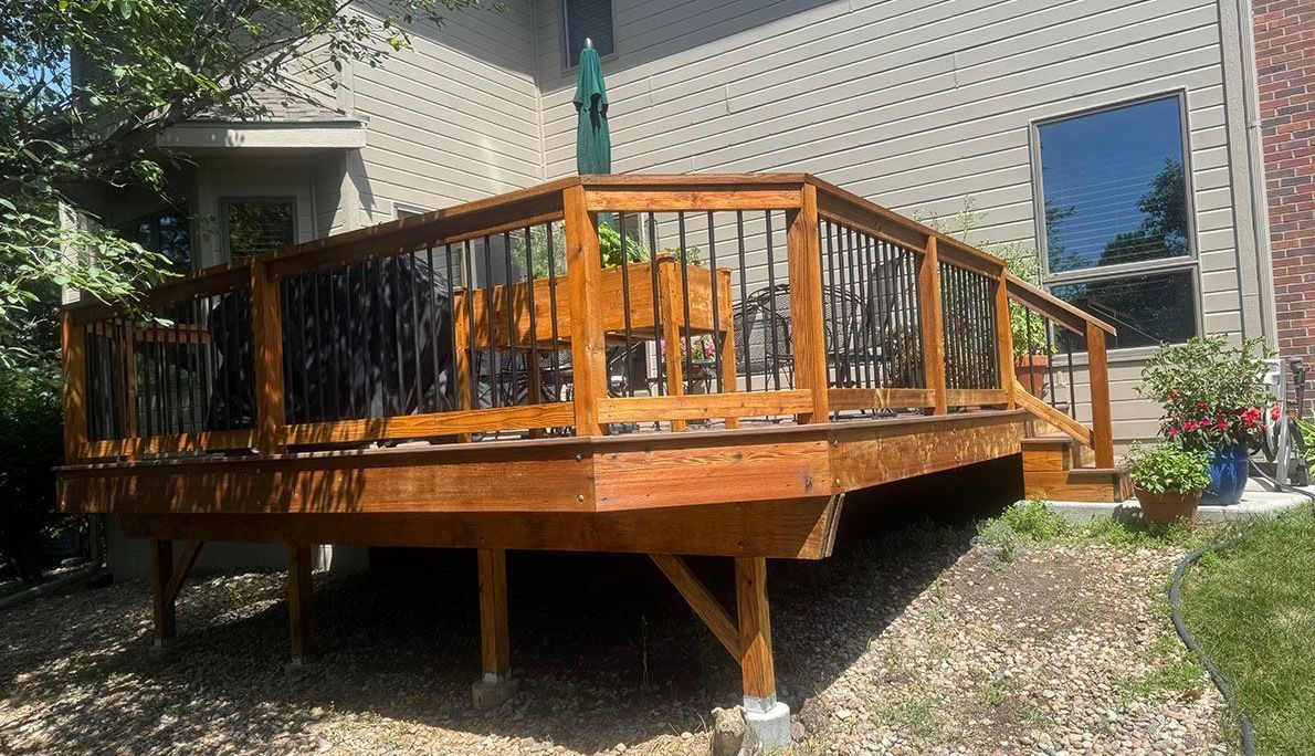 A wooden deck with chairs and umbrellas in front of a house.