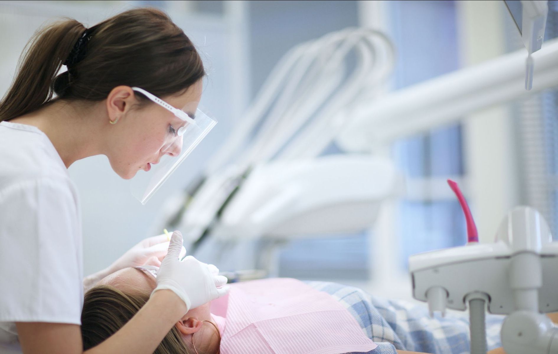 An older woman is smiling and pointing at her teeth.