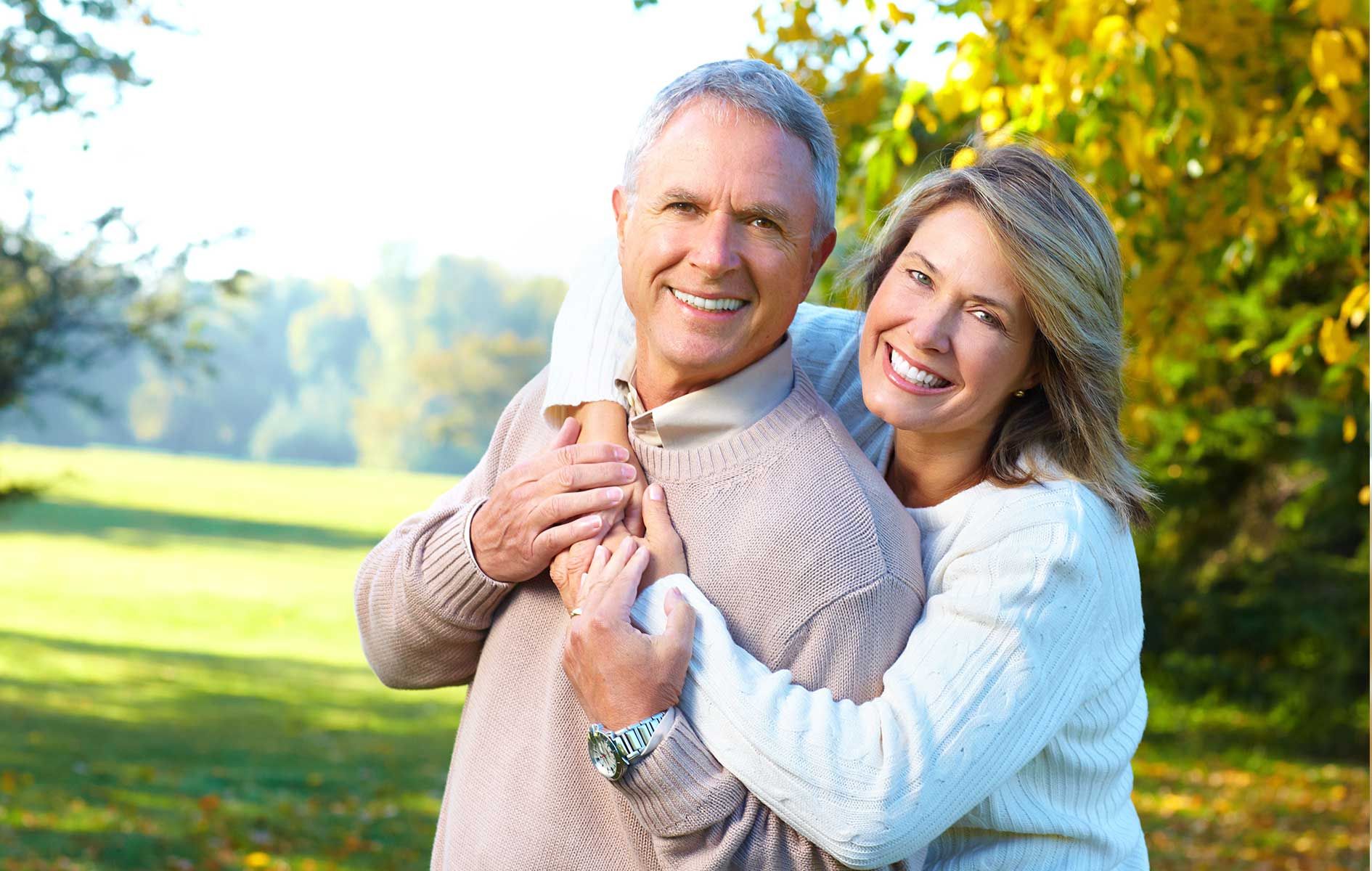 A woman is hugging a man in a park.