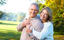 A woman is hugging a man in a park.