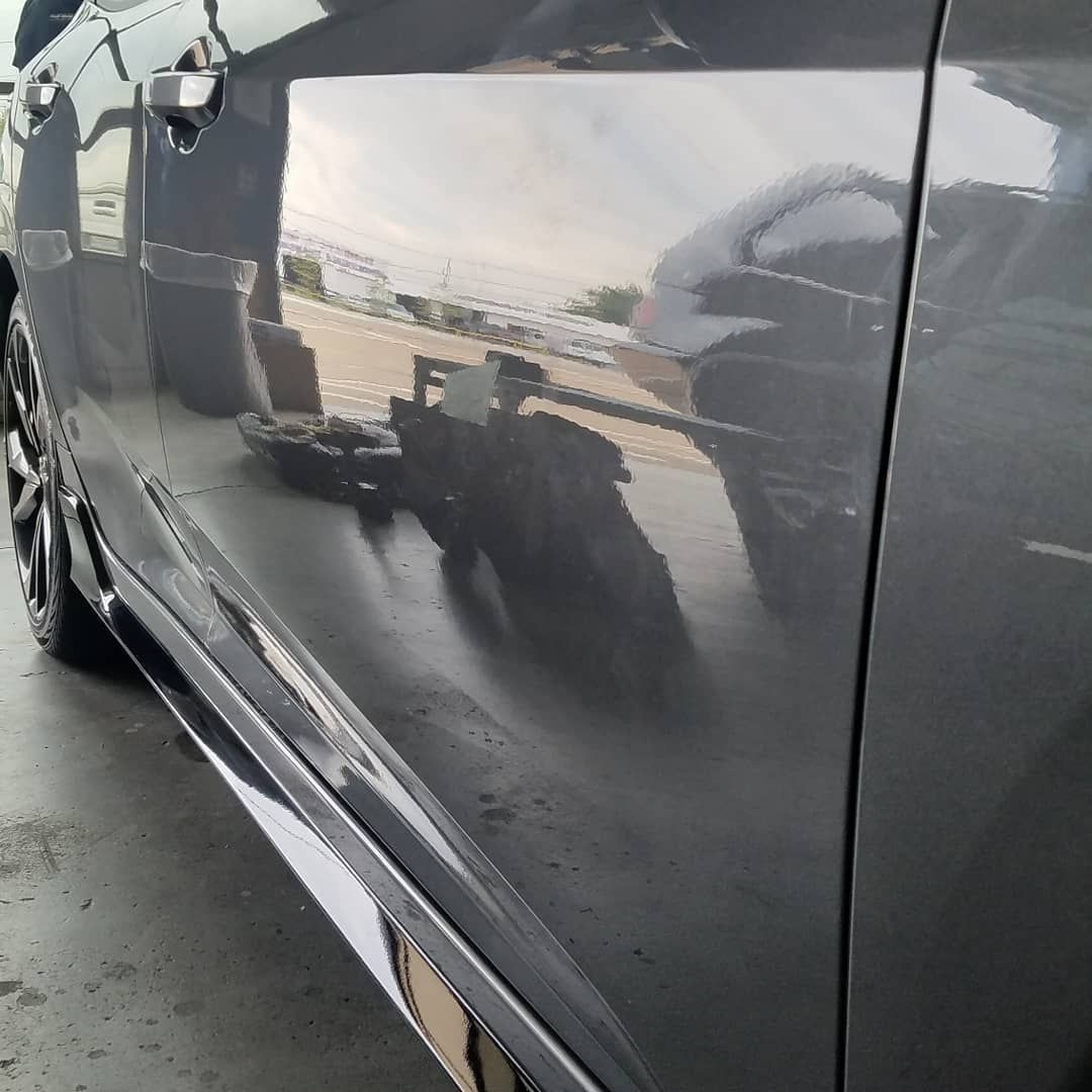 A black car with a reflection of a motorcycle in the door