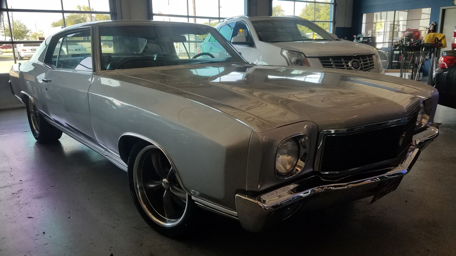 A white car is parked in a garage next to another car.