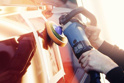 A person is polishing a car with a machine.