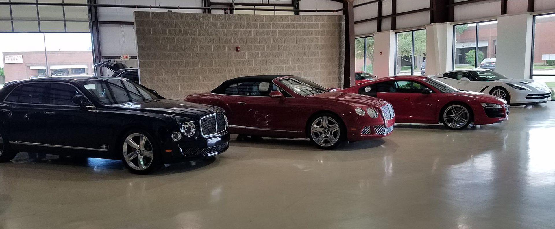 A row of cars are parked in a showroom.