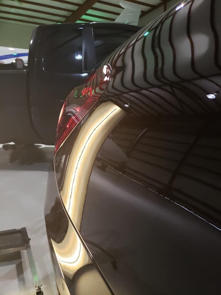 A close up of a black car with a damaged fender