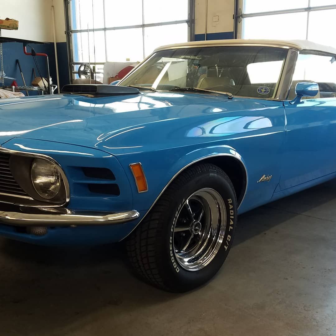 A blue mustang convertible is parked in a garage