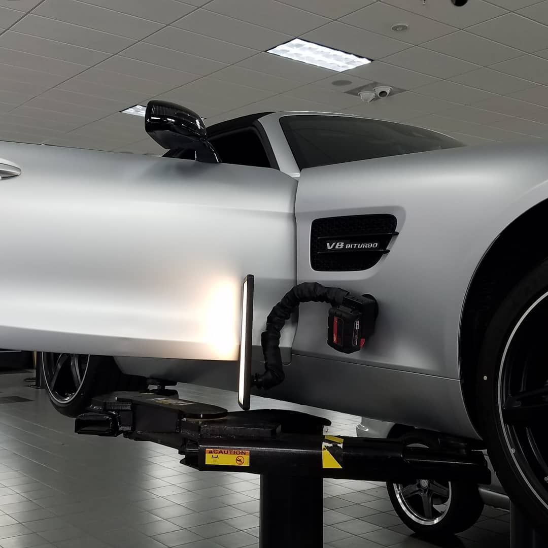 A silver sports car is on a lift in a garage