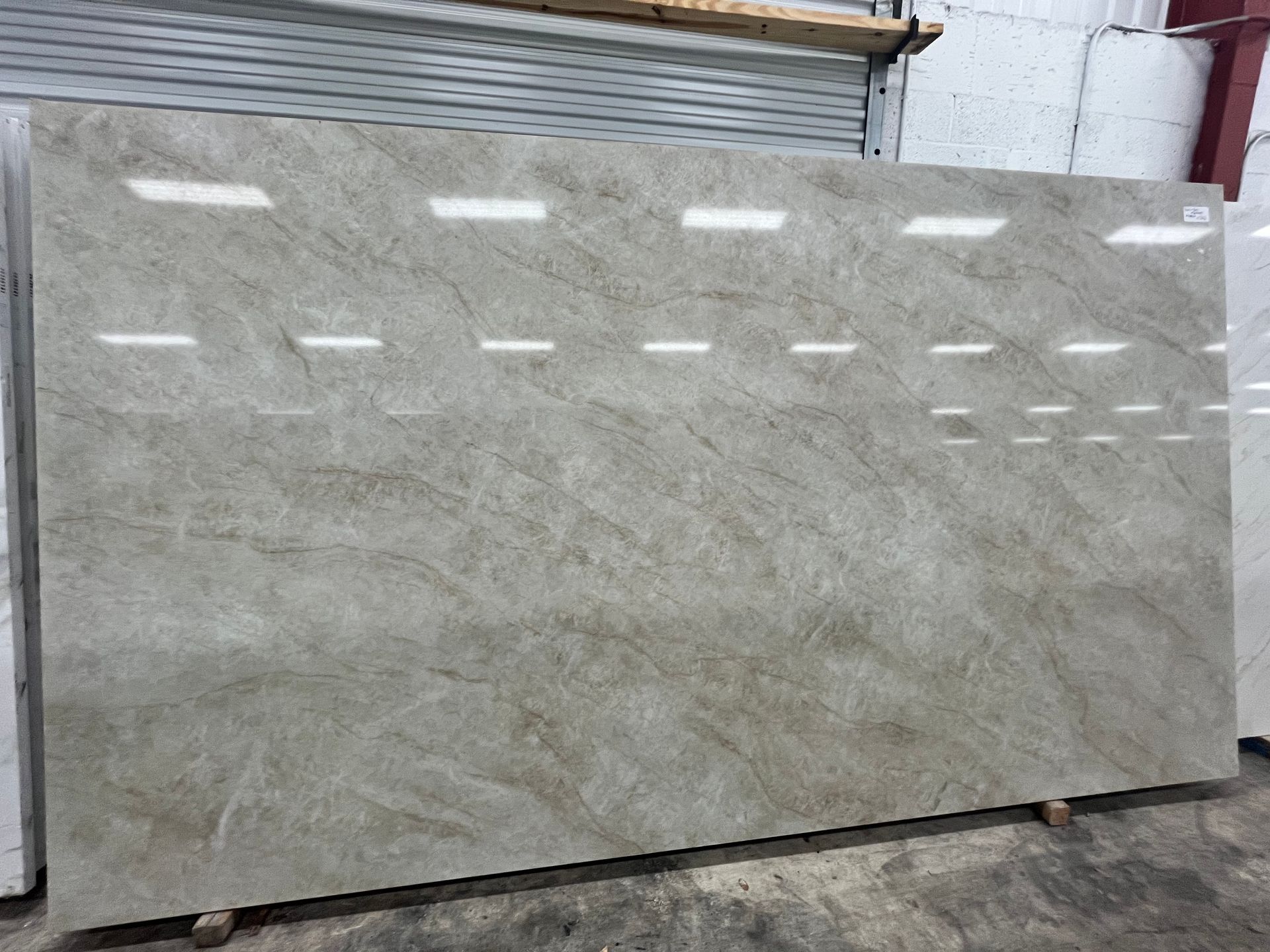 Large gray stone slab leaning against a wall outdoors.