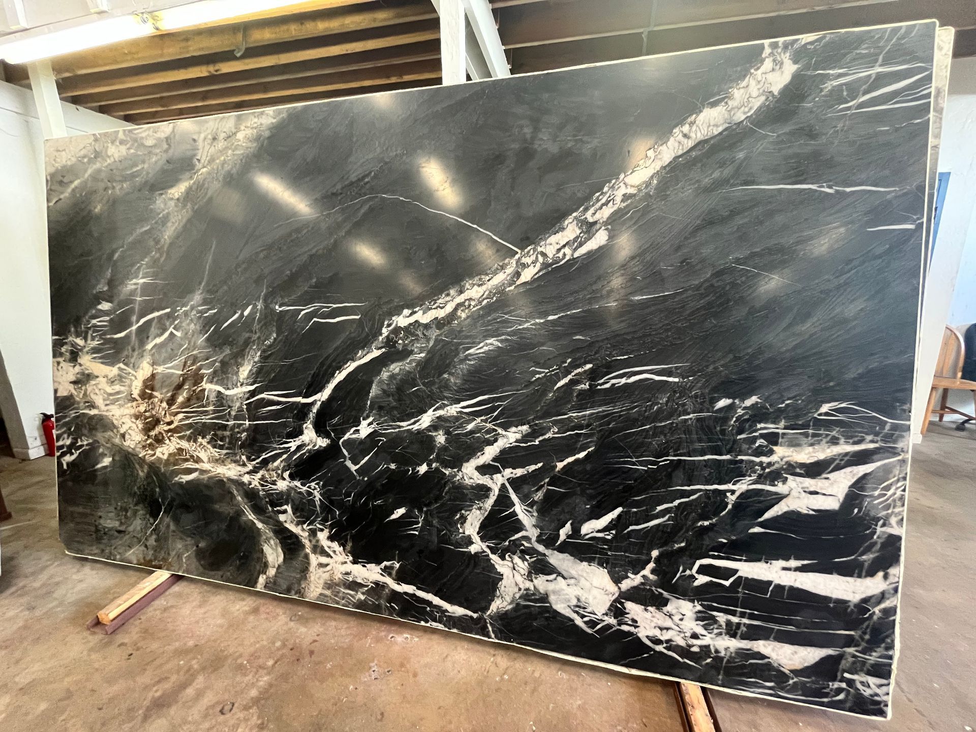 Large black marble slab with white veining, leaning upright in a workshop.