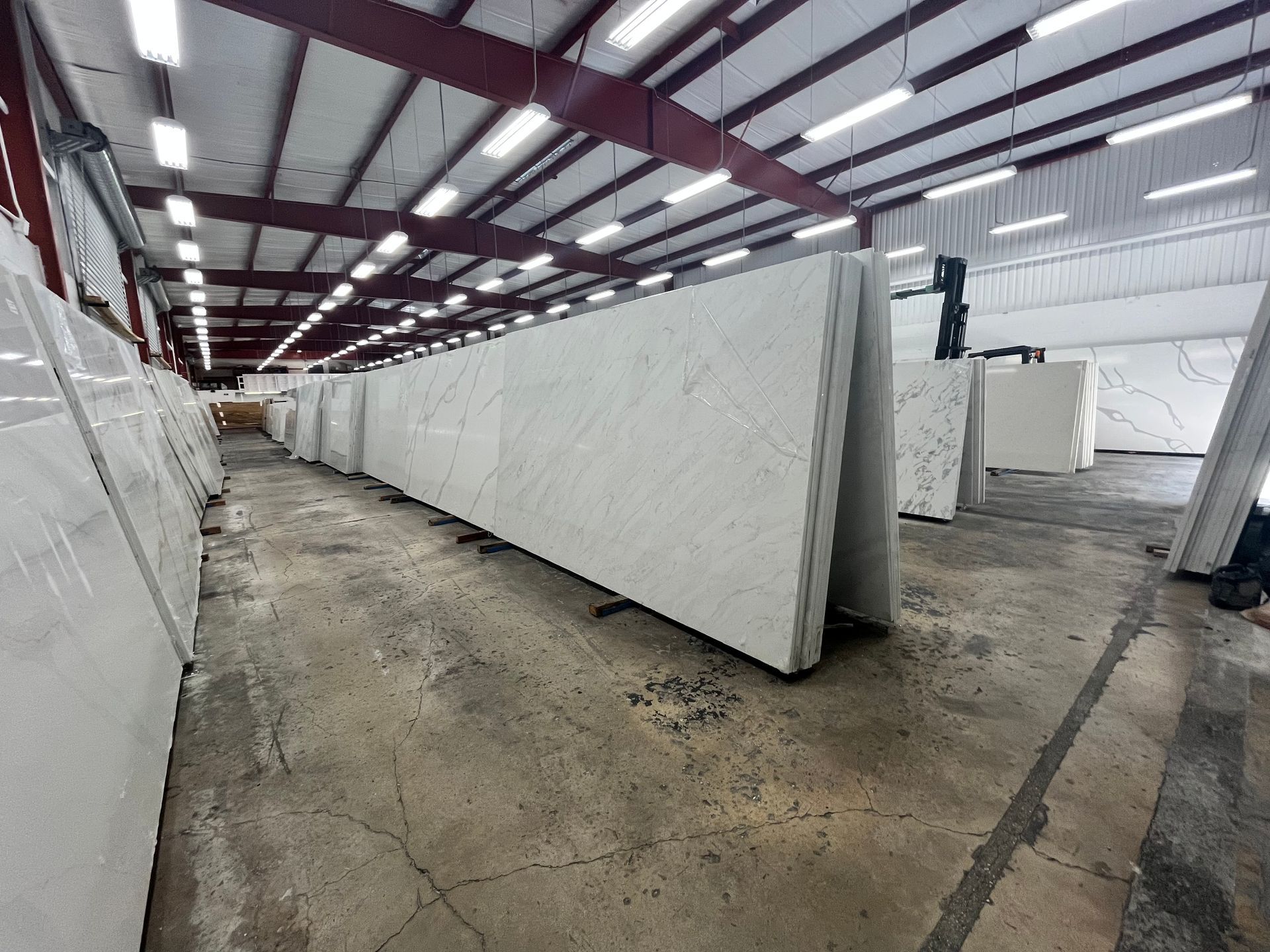 Large white stone slabs standing upright on metal racks in a brightly lit industrial warehouse.