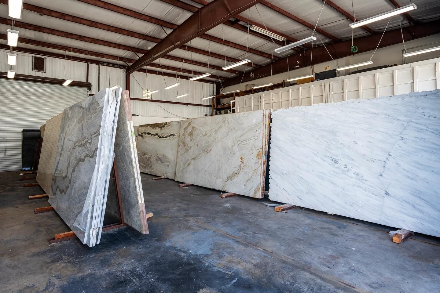 Large stone slabs of varying patterns and colors displayed in a warehouse setting.