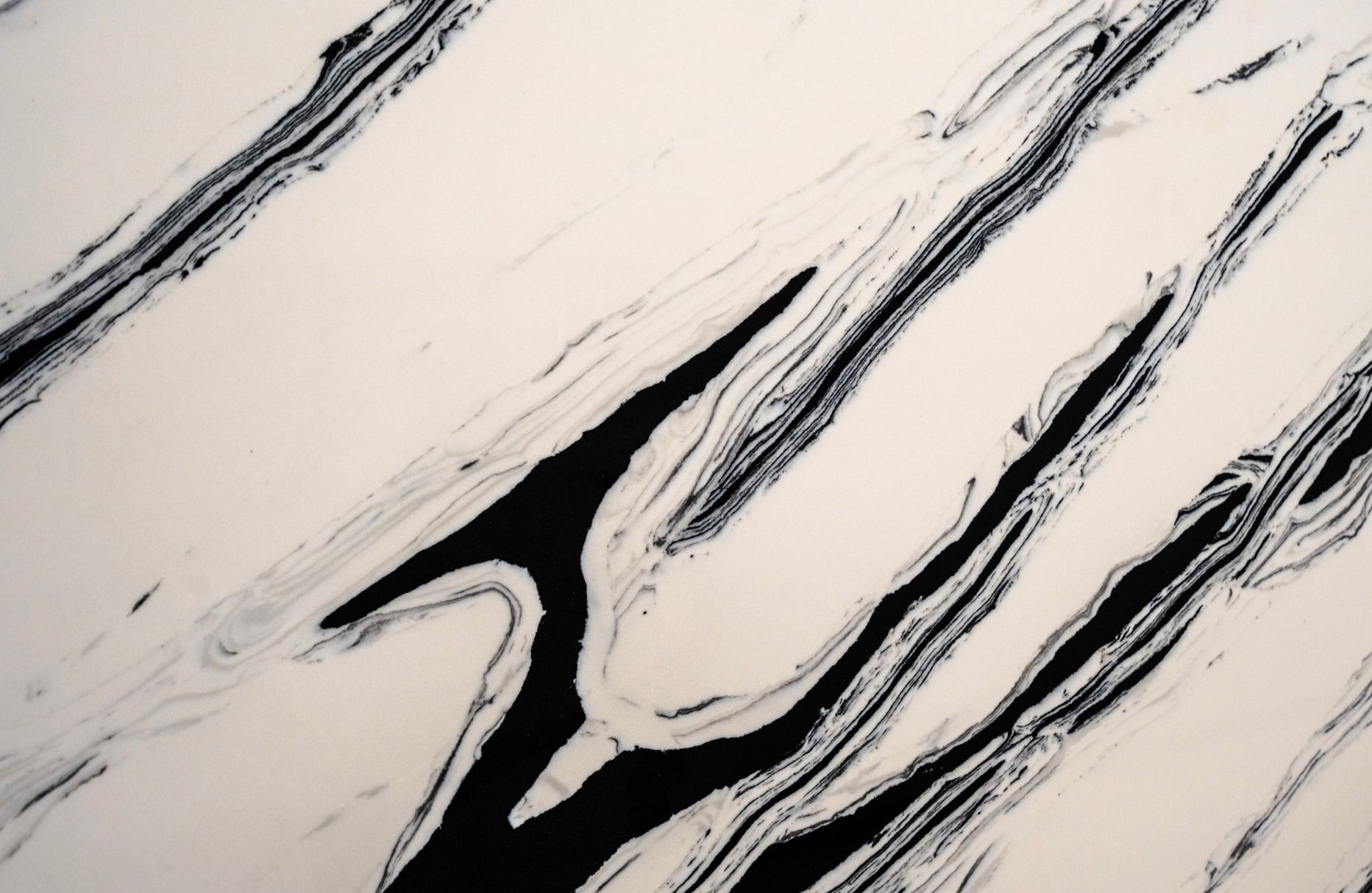 A textured surface with swirling black and white marble-like patterns in long, flowing diagonal streaks.