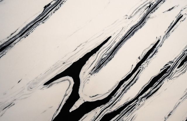 A textured surface with swirling black and white marble-like patterns in long, flowing diagonal streaks.