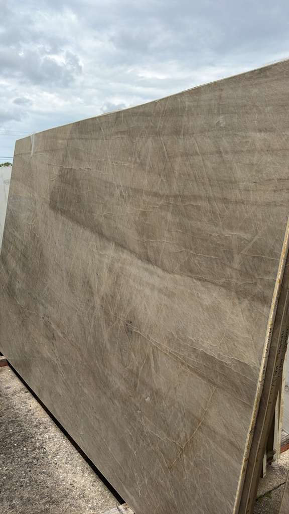 Large beige tarp or fence panel beside a gravel path under a cloudy sky