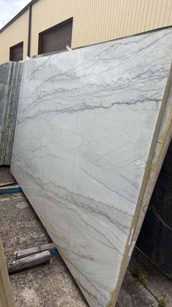 Large white marble slab leaning against a beige building outdoors