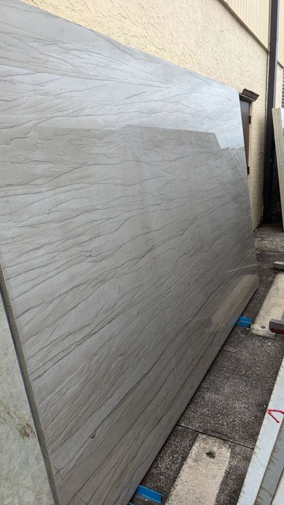 Gray textured wall along a narrow outdoor alley beside a beige building.