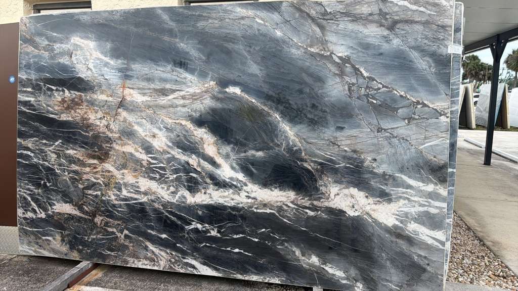 Large polished gray-and-white marble slab with dark veining displayed outdoors