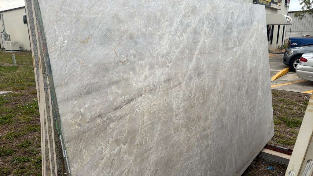 Large gray stone slab outdoors near a building and parked car