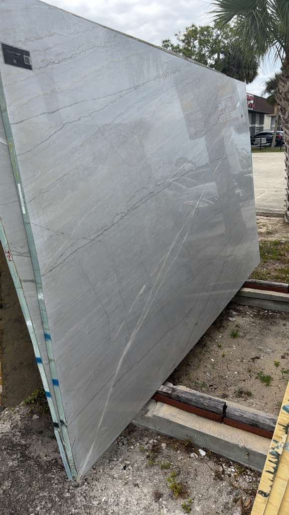 Large gray panel leaning on a metal frame outdoors on a driveway or construction site.