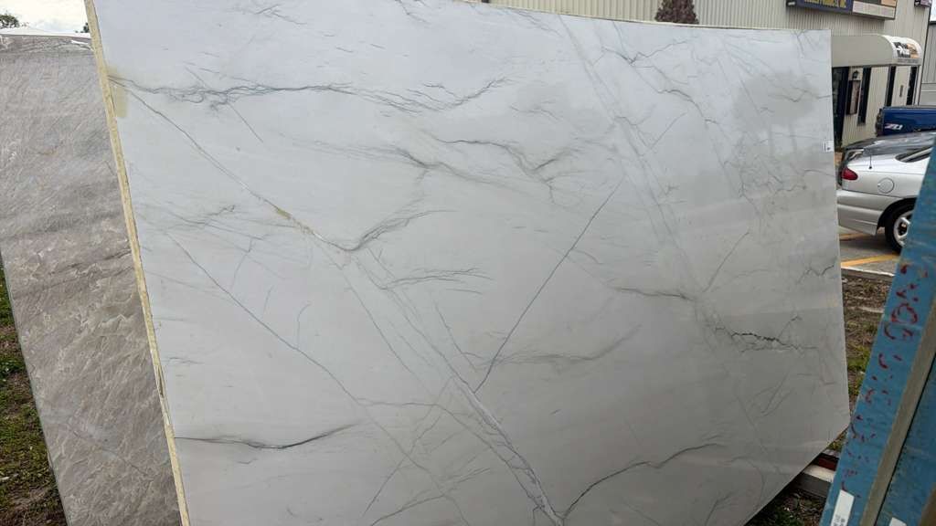 Large white marble slab with subtle gray veining displayed outdoors on a worksite