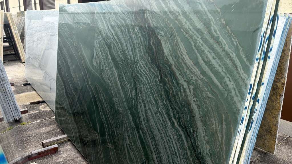 Large green marble slab leaning on supports in a stone yard