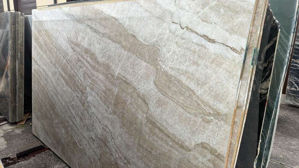 Large polished marble slabs stacked outdoors in a stone yard.