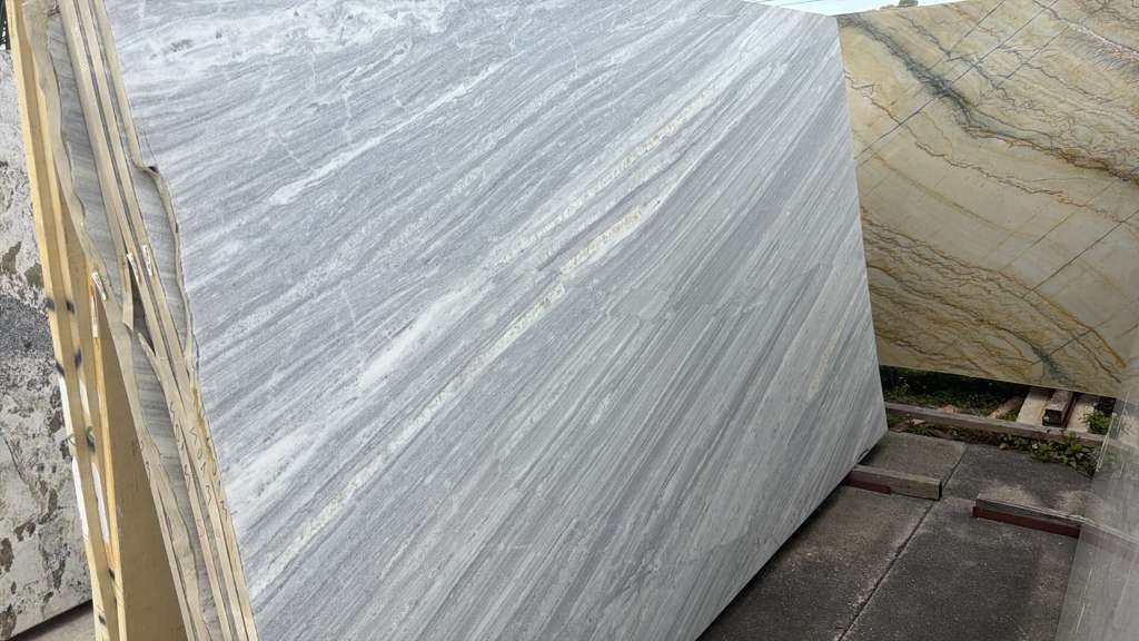 Large white marble slab leaning on a rack in a stone yard.