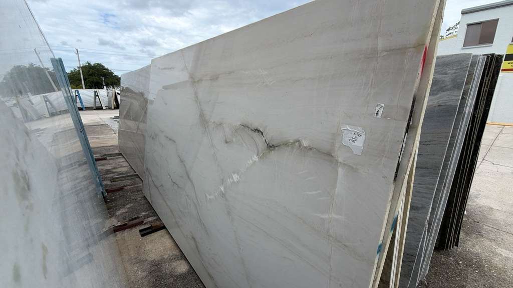 Cracked white stone slab leaning outdoors in a yard or storage area