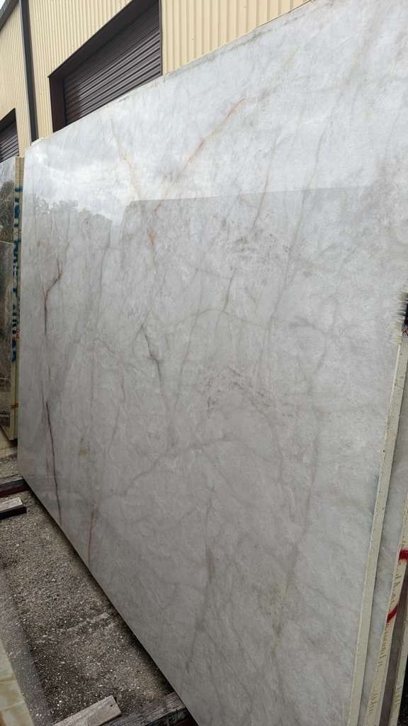 Large white marble slab leaning against a building wall in a narrow outdoor alley