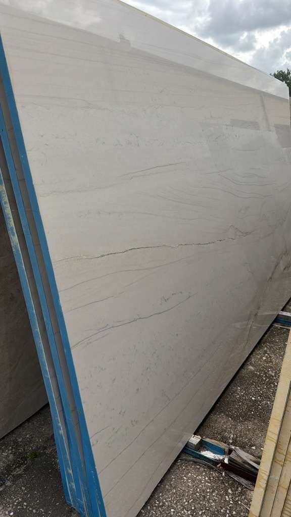 Large gray panel with blue edge standing outdoors on a gravel surface.