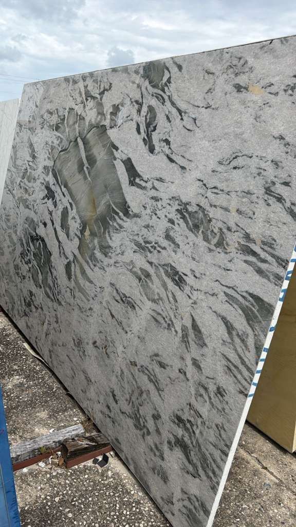 Large rectangular slab of white and gray marble leaning outdoors on pavement