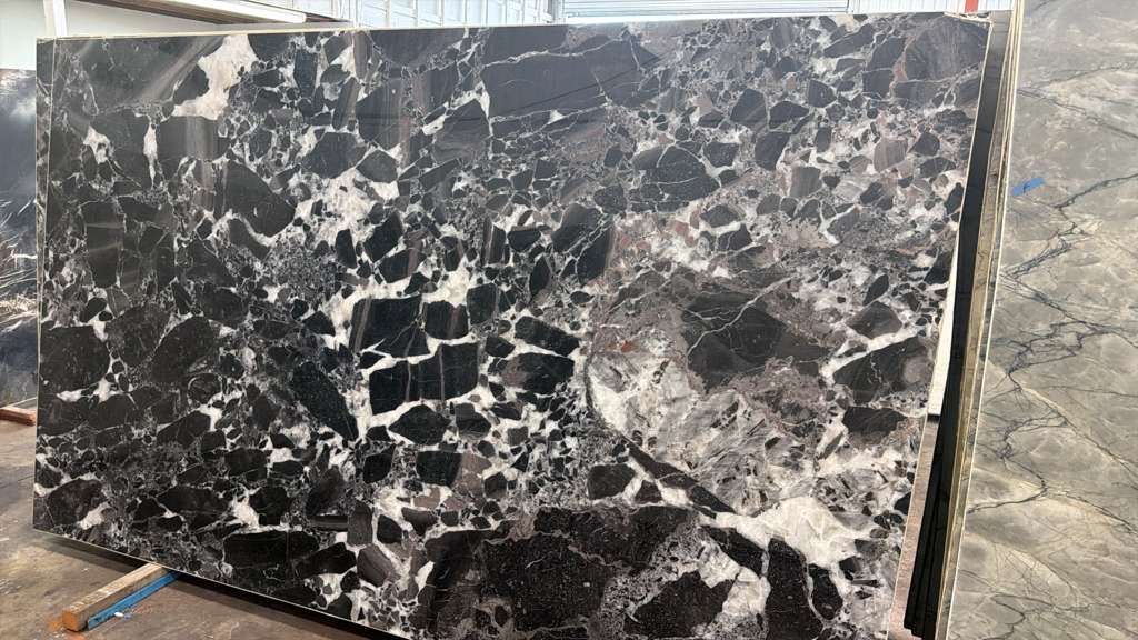 Rectangular black and white marbled stone slab leaning outdoors on a rough surface