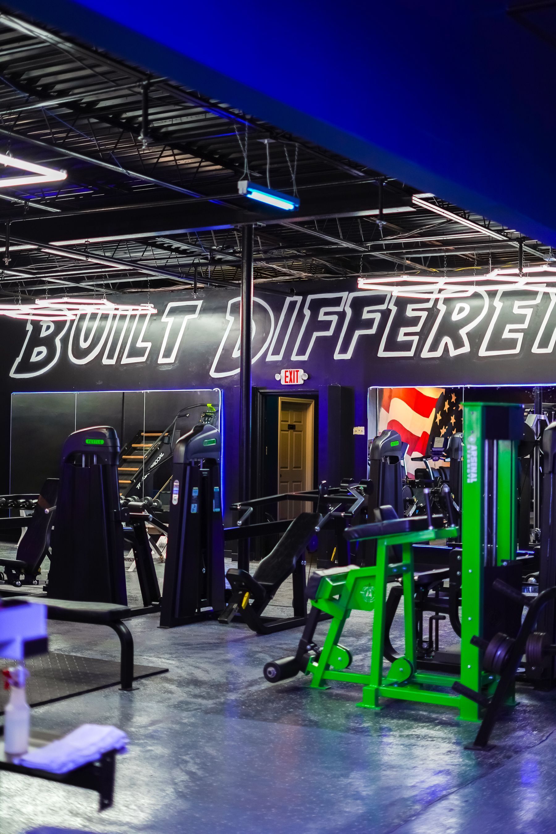 A gym with a lot of equipment and a sign that says `` built different ''.