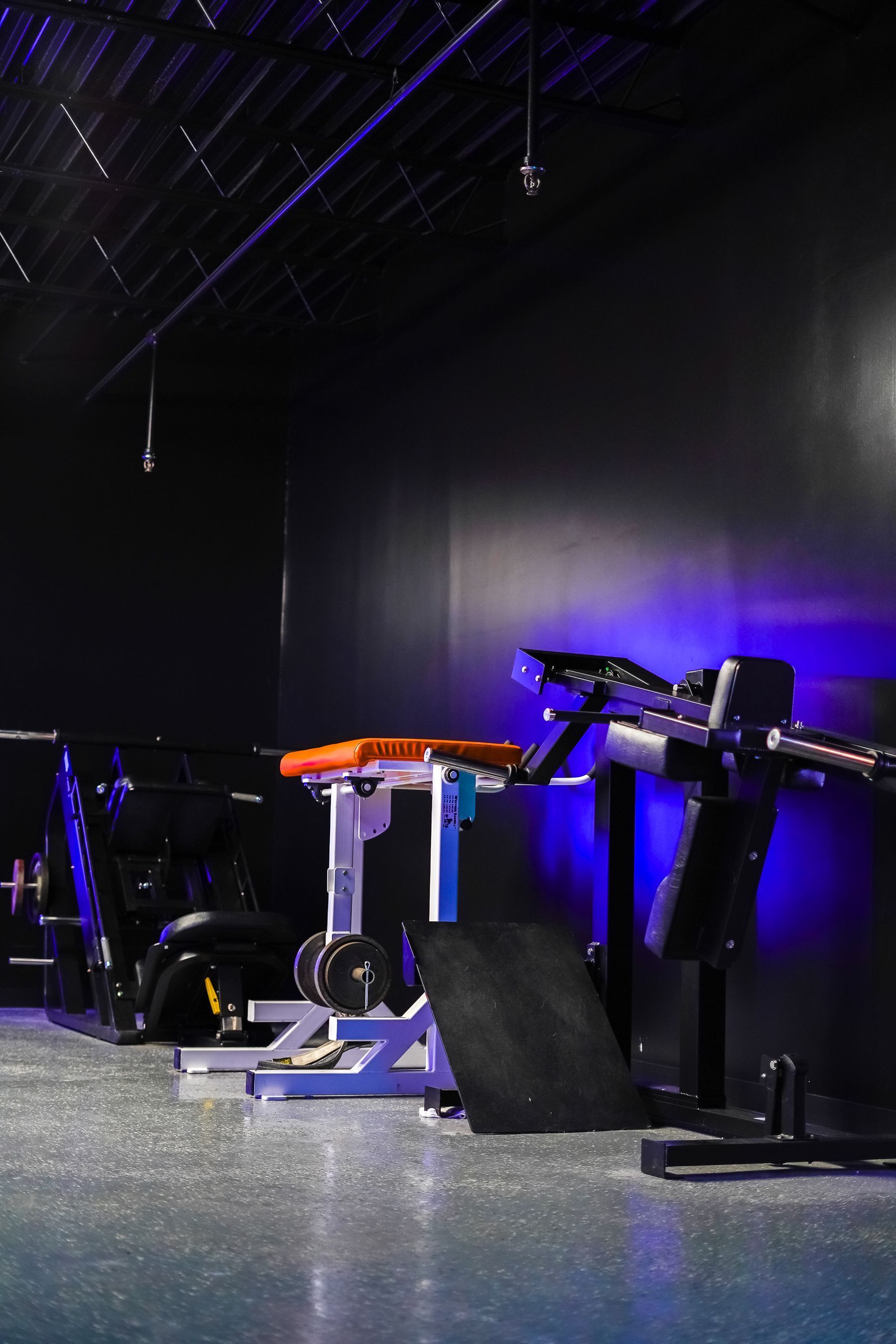 A gym with a lot of exercise equipment and purple lights.
