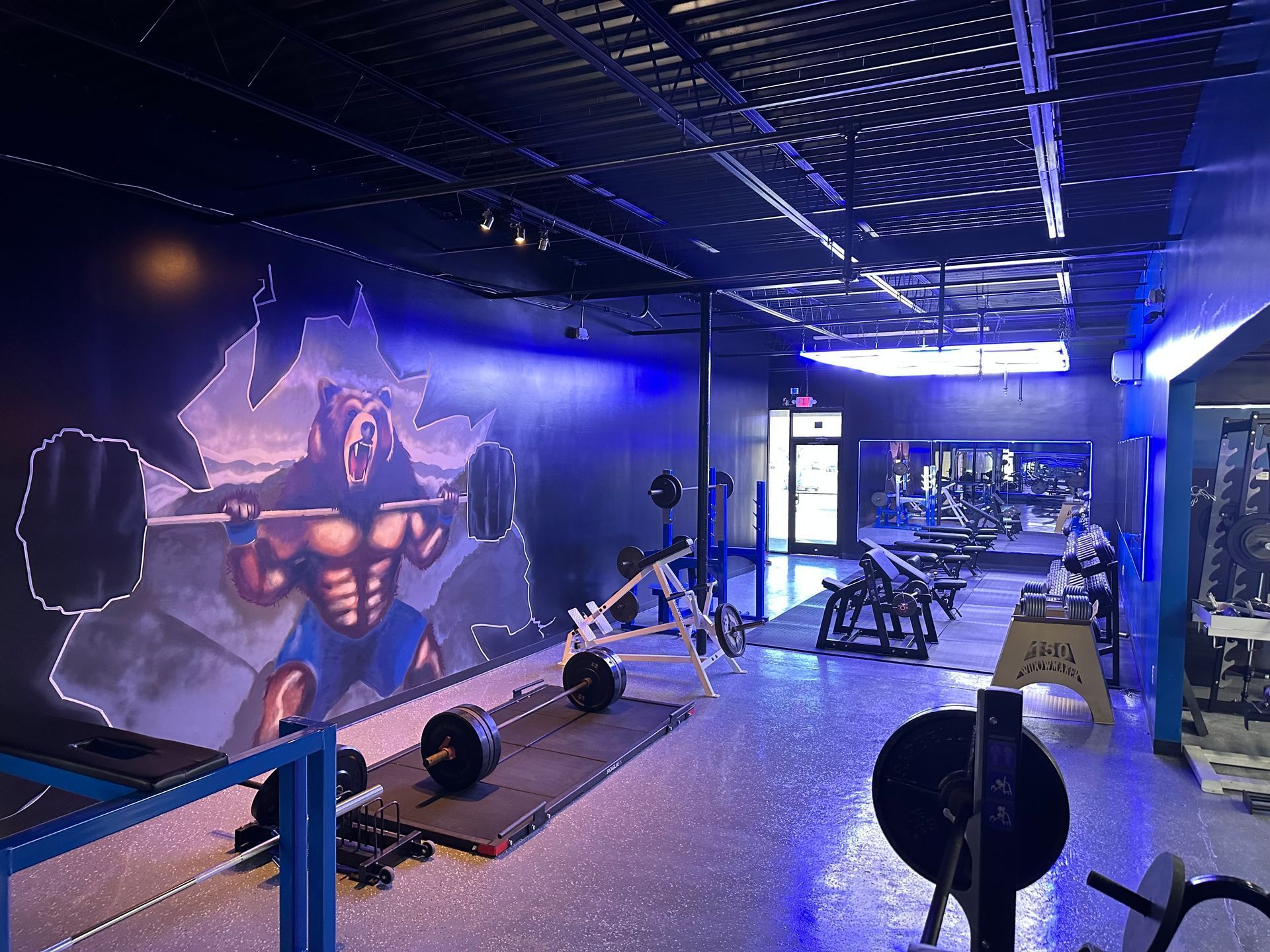 A gym with a painting of a man lifting a barbell on the wall.