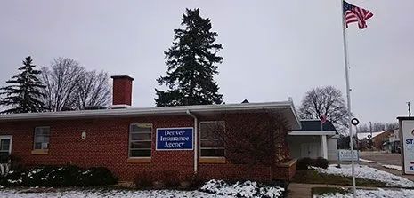 Brick building with a blue sign and an American flag flying outside on a snowy day