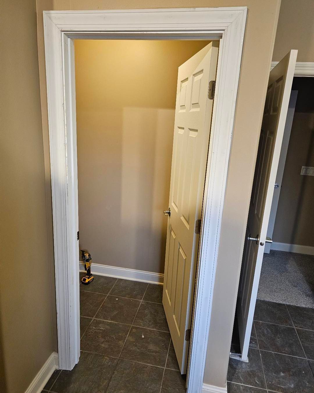 A door is open in a room with a white trim.