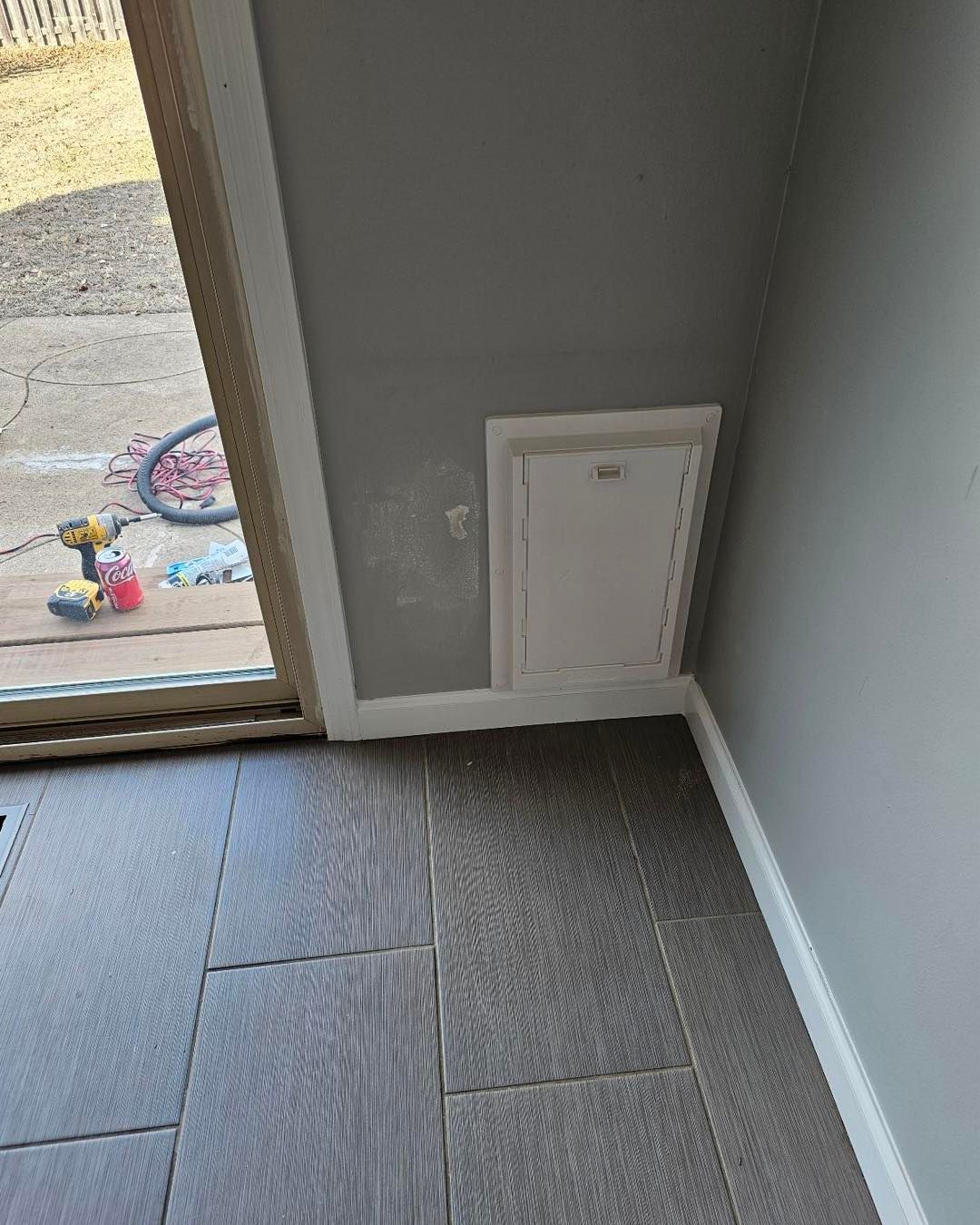 A room with a sliding glass door and a dog door.