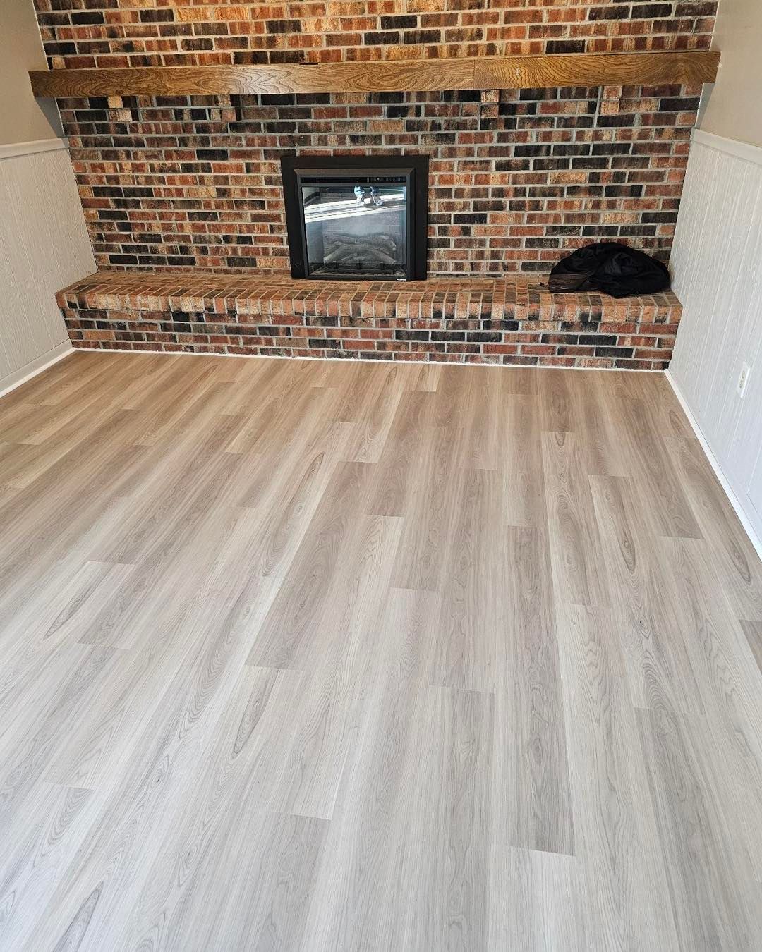 A living room with a fireplace and a brick wall.