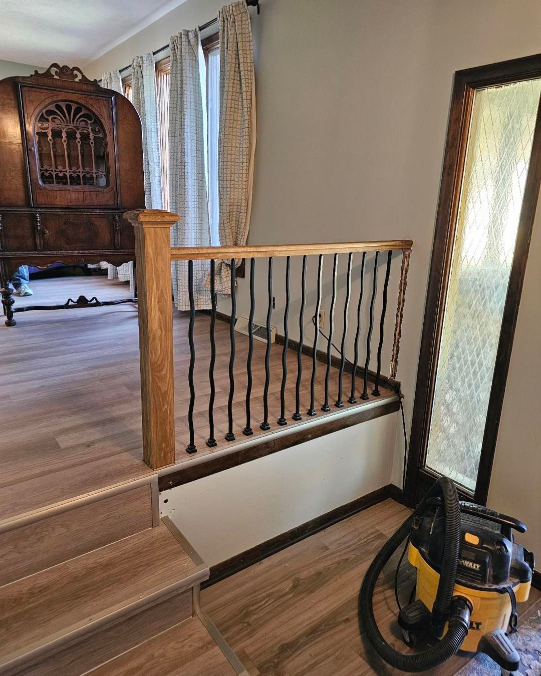 A vacuum cleaner is sitting on the floor in a room next to the stairs.
